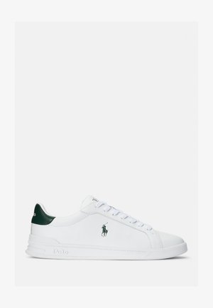 Hvit lær sneakers med grønn hælforsterkning, rund tå og flat gummisåle. Har logo og snøring. Glatt tekstur, minimalistisk stil.