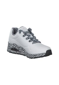 Baskets blanches de sport avec semelle à motif ondulé noir et blanc, lacets et doublure intérieure, avec un coussin d’air visible au talon.
