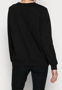 Czarna bluza z miękkiego materiału, z okrągłym dekoltem, ściągaczami przy mankietach oraz luźnym krojem, z gładkim tyłem.