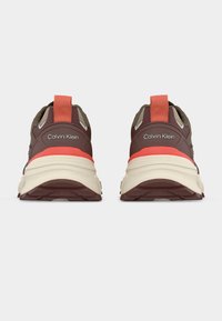 Ζευγάρι καφέ και μπεζ αθλητικά παπούτσια Calvin Klein με κοραλλί λουράκια, εμφανιζόμενα από πίσω σε λευκό φόντο.