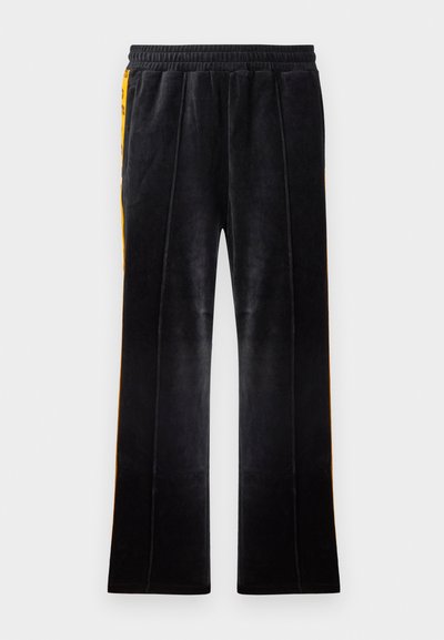 Czarne welurowe spodnie dresowe o rozszerzanym kroju, z elastycznym pasem i żółtymi paskami po bokach. Posiadają pionowe przeszycia dodające detalu.