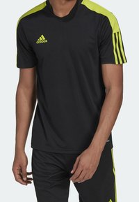 Black athletic shirt with short sleeves, featuring neon green accents on shoulders and three stripes on sleeves. Made of breathable material.