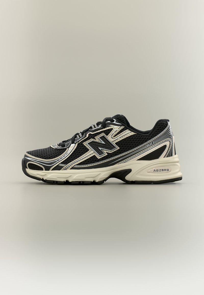 Chaussure de running New Balance noire et beige avec tige en mesh, lacets et semelle amortissante étiquetée "ABZORB" et numéro de modèle "110."