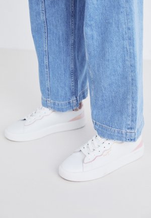 White sneakers with pink accents and white laces. Paired with light-blue, wide-leg denim trousers, cropped at the ankle. Smooth texture.