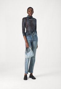 Zwarte slangenprint lange mouw top, blauwe denim jeans, korte blauwe handtas, zwarte instappers. Slim fit, textuurstof en hoge hals.