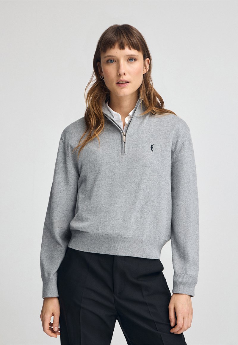 Maglione grigio a collo alto con zip. Tessuto a maglia con polsini e orlo a costine. Presenta un piccolo logo sul petto.