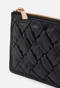 Sort læderpung med vævet struktur, prydet med en gylden lynlås og hardware. Nærbillede viser detaljeret håndværk og glat finish.