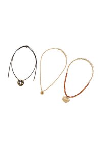 Trzy naszyjniki: czarny sznurek z okrągłym wisiorkiem, złoty łańcuszek z małym dyskiem oraz złoty łańcuszek z bursztynowymi koralikami i teksturowanym wisiorkiem.