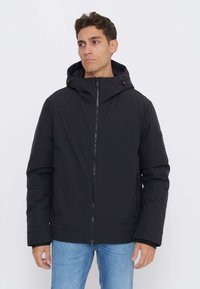 Sort hættetrøjejakke med lynlåslukning foran, sidelommer, lavet af glat, letvægtsstof med et enkelt design og minimale detaljer.