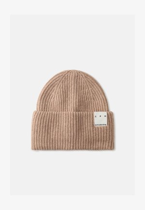 Beige strikket hue med ribbet tekstur, foldet kant og et mærke med "CPH STUDIOS." Stoffet ser blødt og varmt ud.
