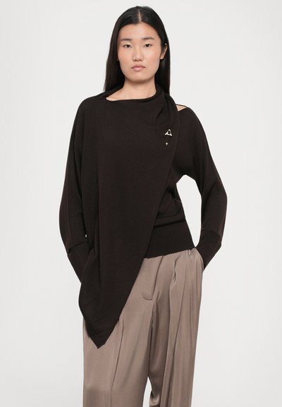 Brown oversized sweater with an asymmetric design, featuring a single shoulder cutout and a small triangular accent detail. Soft texture.