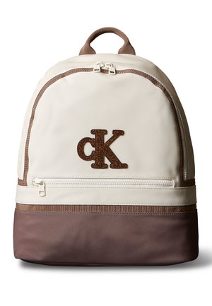 Sac à dos crème et marron avec poche zippée à l'avant et logo marron "cK" centré sur la partie supérieure avant.