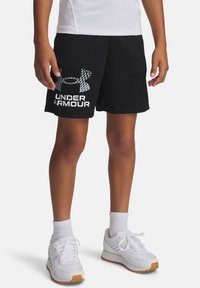 Čierne športové šortky s bielym logom "Under Armour", s textúrou pripomínajúcou sieť a elastickým pásom, skombinované s bielymi teniskami a ponožkami.