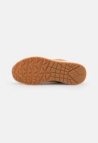 Gummisohle mit einem strukturierten Grip-Muster, das diagonale und dreieckige Stollen in Orange aufweist und für Traktion und Langlebigkeit sorgt.