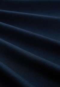 Tissu bleu marine foncé avec des plis doux et une texture fine, présenté en gros plan, mettant en avant une surface lisse et régulière.