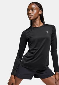 Black long-sleeve athletic shirt made of moisture-wicking fabric, paired with black shorts. Shirt features a logo on the left chest.