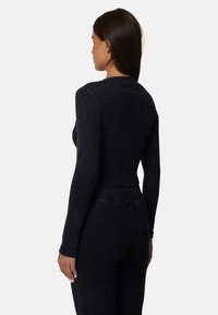 Czarna, prążkowana bluzka z długim rękawem o dopasowanym kroju, z okrągłym dekoltem i bezszwowym wykończeniem. Teksturowana tkanina o gładkim wykończeniu.