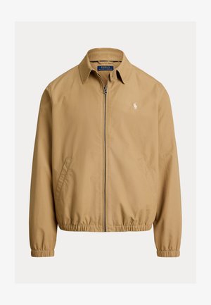 Kurtka zapinana na zamek w kolorze beżowym, z kołnierzem, elastycznymi mankietami i dołem. Posiada boczne kieszenie oraz małe wyszywane logo na piersi.