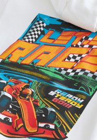Balta sportinė megztinė su kapišonu, puošta spalvingu grafiniu lenktyninio automobilio, languotų vėliavų ir ryškių užrašų „LET'S RACE“ bei „READY STEADY GO!“ vaizdu.