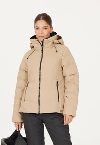 Beige isoleret jakke med lynlås foran, snorhuv og sorte lynlåsdetaljer. Har to forvasker og en blød indvendig foring.
