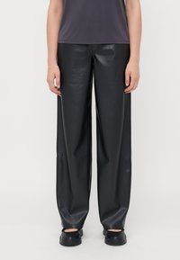 Pantalons large en simili cuir noir avec une texture lisse, présentant une taille moyenne et un design minimaliste. Coupe droite de la hanche à l'ourlet.