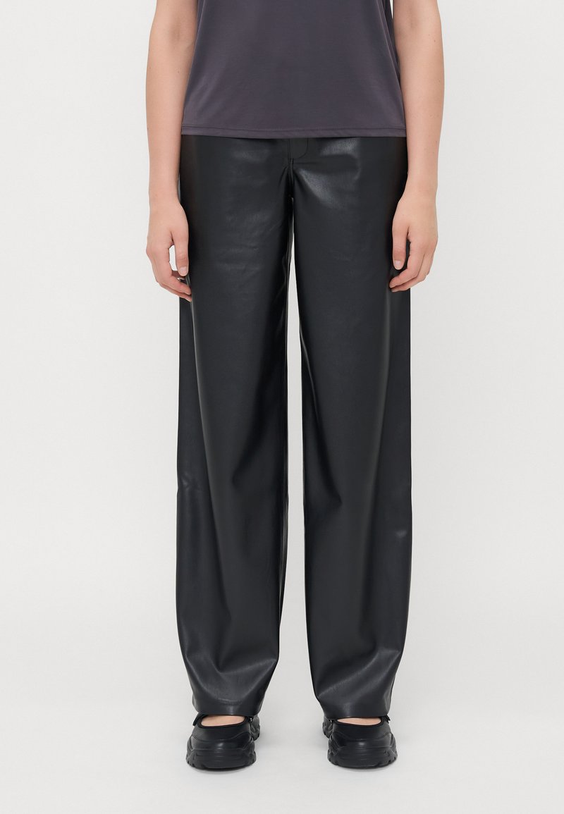 Pantalons large en simili cuir noir avec une texture lisse, présentant une taille moyenne et un design minimaliste. Coupe droite de la hanche à l'ourlet.