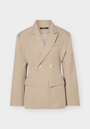 Μπεζ διπλόπασσο σακάκι με λοξά πέτα, δύο κουμπιά, τσέπες με καπάκι και τσέπη στο στήθος, εμφανισμένο σε απλό φωτεινό φόντο.