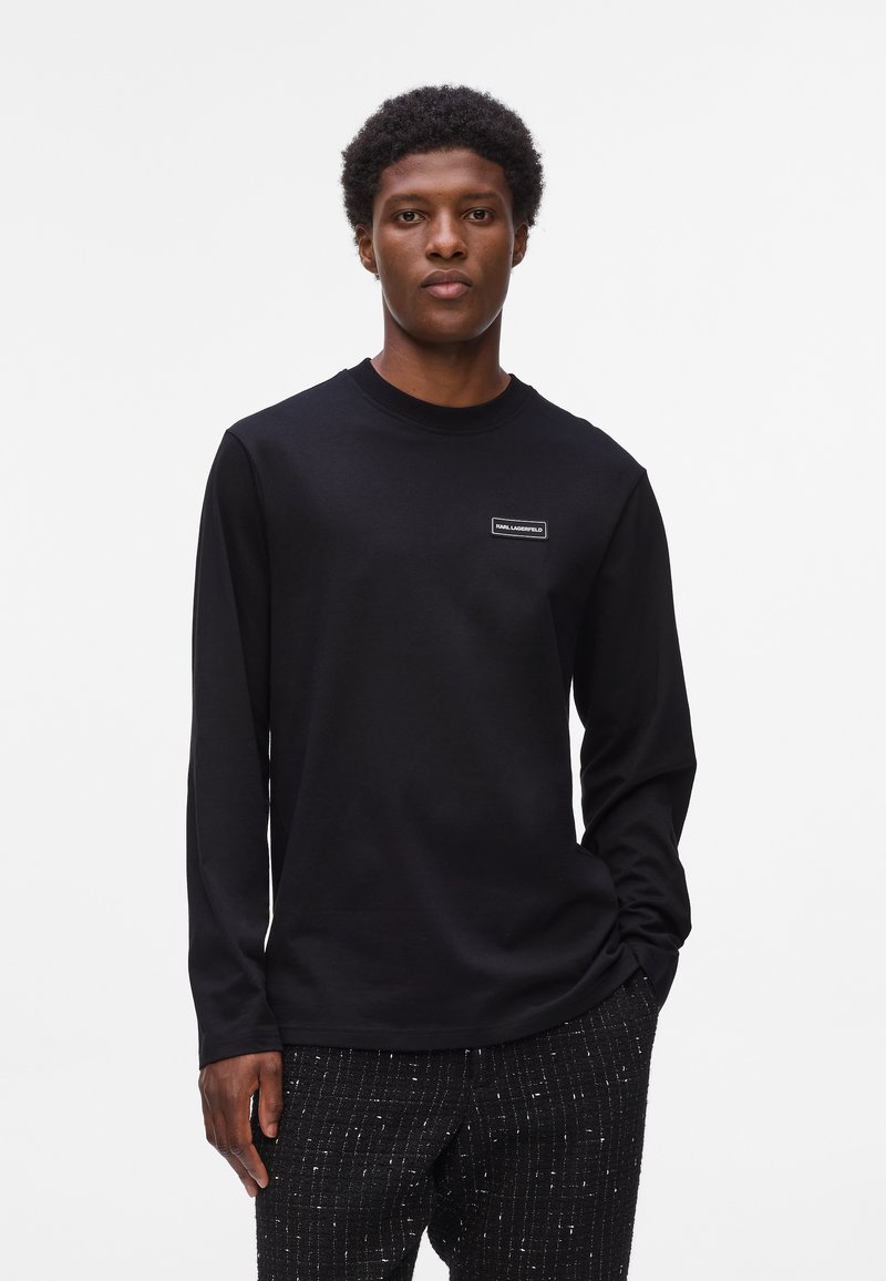 Sort langærmet T-shirt med rund hals i blødt stof, har et lille rektangulært logo på brystet og en afslappet pasform.