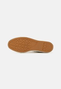 Sola de sapato de borracha com uma textura pegajosa de cor mel, apresentando padrões em diamante e uma borda branca. Marcas para identificação da marca incluídas.