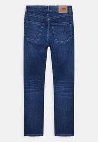 Mörkblå denimjeans med rak bendesign, som har två bakfickor och en brun läderlogotyp på midjan.