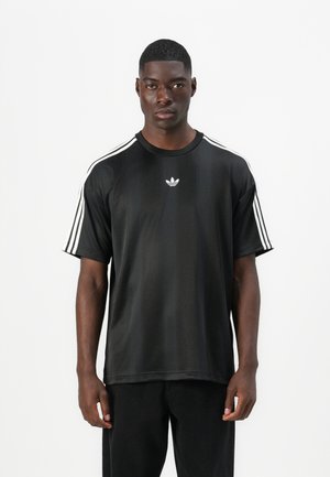 Fekete sportos rövid ujjú póló, fehér háromcsíkos díszítéssel a vállakon és egy kis fehér logóval a mellkason. Simább textúrájú anyag.