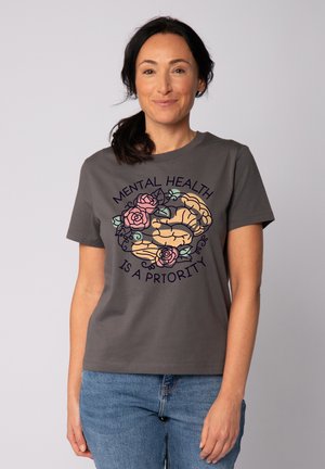 Grijze katoenen T-shirt met kleurrijke hersenen en rozenafbeelding, vergezeld van de tekst "MENTALE GEZONDHEID IS EEN PRIORITEIT" in een gebogen ontwerp. Korte mouwen.