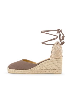 Hnedý uzavretý klinový espadrille s pletenou podrážkou z juta a viazacími pásikmi okolo členka, s tkanou pätou a uzlíkovými koncami na remienkoch.