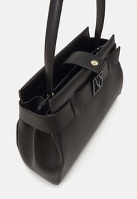 Schwarze Handtasche aus strukturiertem Material mit einer formstabilen Form. Sie verfügt über eine große Öffnung, zwei Griffe und ein dekoratives Verschlussdetail.