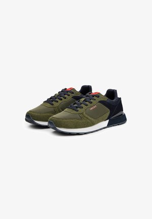 Zapatillas deportivas verdes con un upper texturizado, acentos en navy y suela blanca. Presentan cordones redondos y un pequeño logo rojo en el lateral.