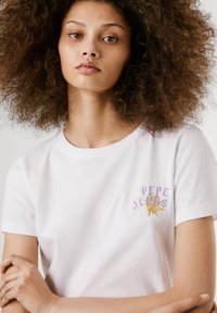 Bílý bavlněný tričko s kulatým výstřihem, krátkými rukávy a barevným vyšívaným logem "PEPE JEANS" na levé straně hrudi.