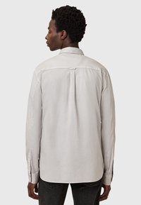 Lichtgrijze longsleeve shirt met een button-down kraag, schouderplooidetails en knoopmanchetten, gemaakt van zachte katoenen stof.