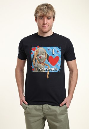 Schwarzes T-Shirt mit einem Grafikdesign eines Plüschtiers, das Würstchen hält, und dem fetten Text "Ich ♥ WÜRSTCHEN!" auf blauem Hintergrund mit Herzen und Wirbeln.