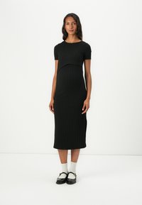 Μαύρο ριγέ μίντι φόρεμα με κοντά μανίκια, εφαρμοστό μπούστο και μήκος κάτω από το γόνατο, συνδυασμένο με μαύρα παπούτσια και λευκές κάλτσες.