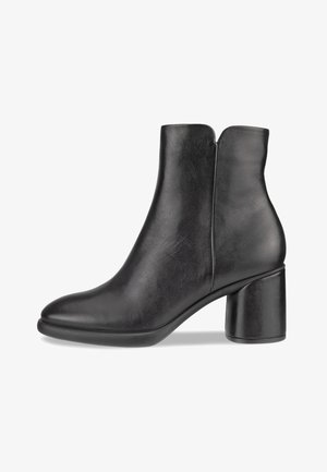 Svart skinn ankelstøvel med rund tå, mid-høy blokkheel og en glatt tekstur. Har utskåret bakside og minimalistisk design.