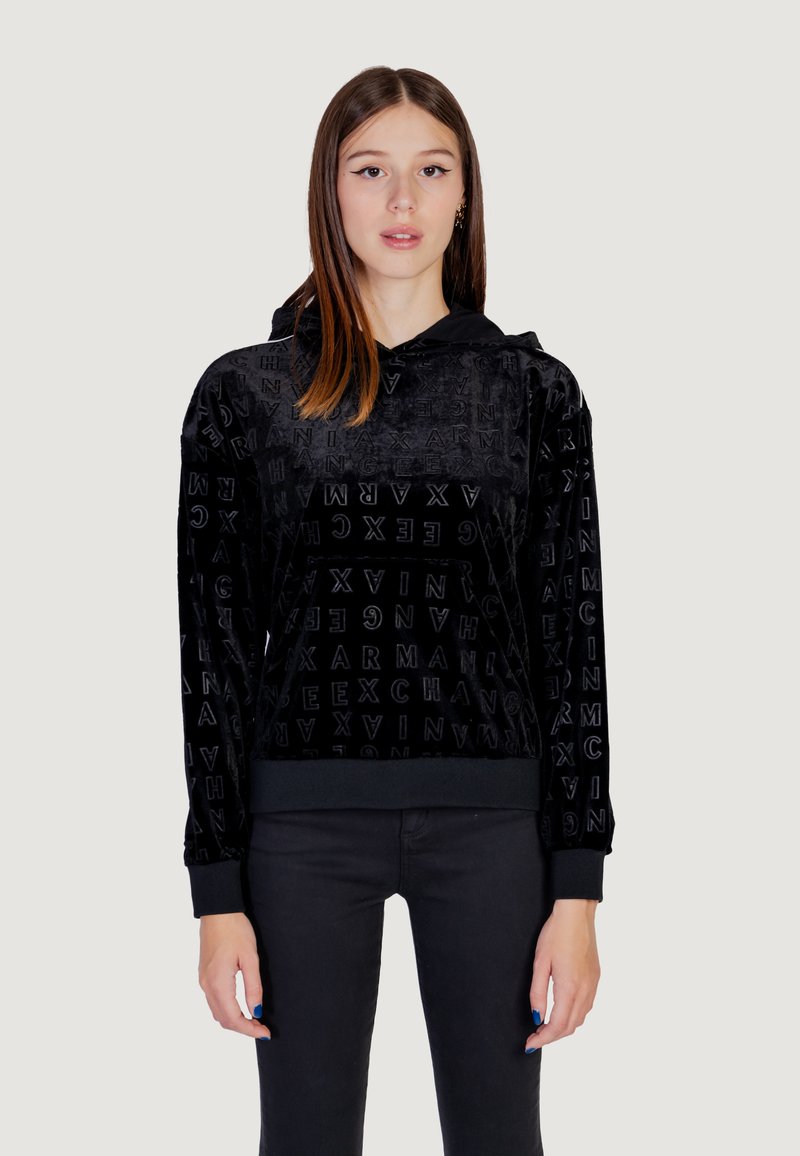 Sudadera de terciopelo negro con patrón de logo en relieve. Cuenta con capucha, mangas largas y puños y dobladillo acanalados. Combinada con pantalones negros.