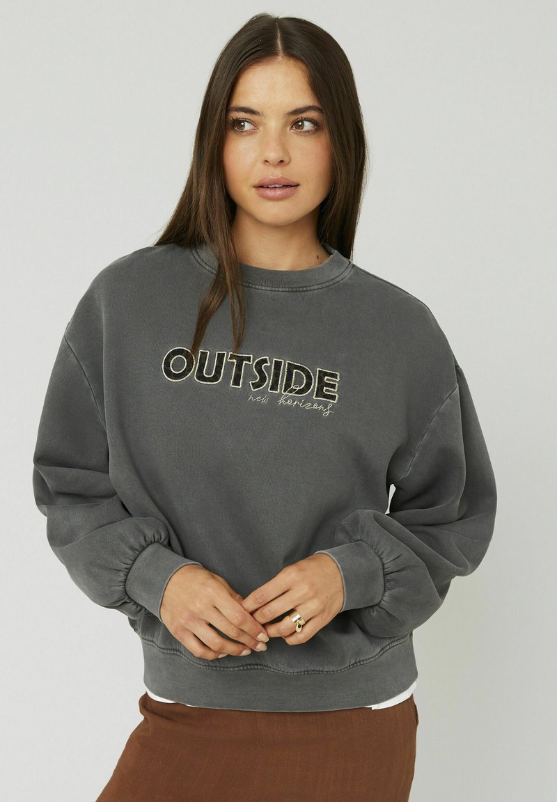 Sweatshirt gris avec un col rond, des poignets élastiques et "OUTSIDE new horizons" brodé sur le devant. Tissu doux avec une coupe décontractée.