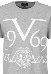 Šedé bavlněné tričko s velkým bílým potiskem s "V" a "1969" a na spodní části s kruhovým designem s emblémem lva.