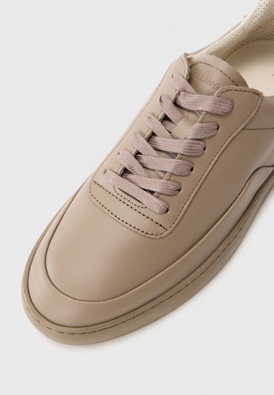 Beige lærersneaker med en glatt, avrundet tå, mesh-foring og taupe snøring. Har diskret søm og et minimalistisk design.