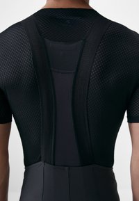 Schwarzer Fahrradanzug mit einem strukturierten Mesh-Rücken, glatten Stoffakzenten und ergonomischem Design mit verstellbaren Trägern für zusätzlichen Komfort.