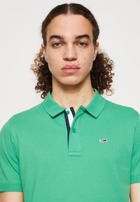 Polo verde realizzato in cotone testurizzato, con colletto e patta con tre bottoni. Piccolo logo sul petto e dettagli blu navy.