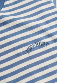 Gestreept katoenen T-shirt met blauwe en witte horizontale strepen. Geborduurd "Superdry" logo in het blauw boven de zoom.