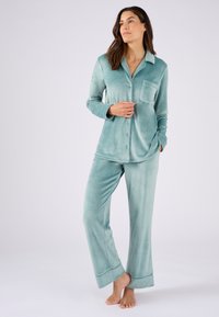 Lichtblauw pyjama set gemaakt van zacht, plush stof; omvat een knoopsluiting shirt met een zak en bijpassende broek met brede manchetten.