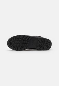 Suela de bota de exterior con patrón de banda de rodadura profundo. Material de goma negra, diseño robusto adecuado para brindar tracción en diversas superficies.