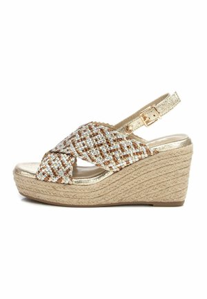 Sandalia cuña con tiras metálicas trenzadas en marrón y dorado, que cuenta con una suela de yute trenzado y una correa de tobillo ajustable.